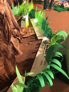 some green plants and trees on display at a convention or show with people in the background