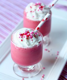 two glasses filled with ice cream and sprinkles on a white platter