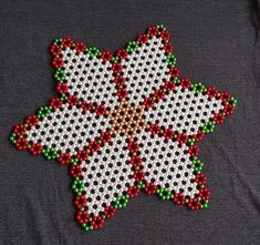 a cross stitched christmas ornament with red, white and green beads in the shape of a star