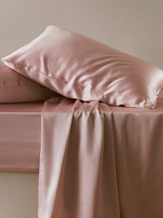 a bed with pink sheets and pillows on it