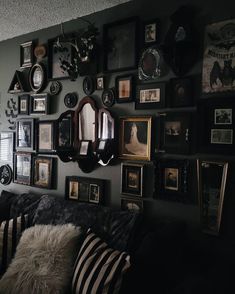 a living room filled with lots of framed pictures on the wall next to a couch