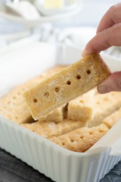 a person dipping crackers into a white dish