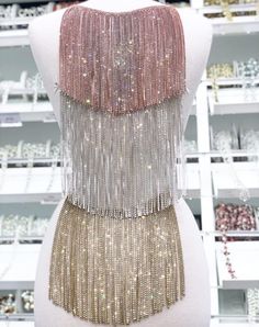 the back of a mannequin with gold and silver beads on it's chest