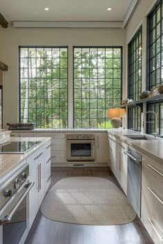 a kitchen with lots of counter space and windows above the stove, sink, and dishwasher