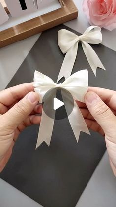 two hands holding a paper bow on top of a table