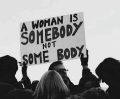 a woman is holding a sign that says, a woman is somebody not some body