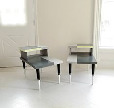 two small tables sitting next to each other on top of a white floor in front of a door