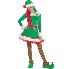 a woman dressed in green and red is standing with her hands on her hips while wearing a santa claus costume