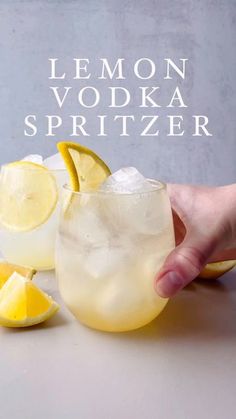 a hand is holding a lemon vodka spritzer