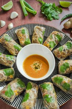 a plate filled with vegetable spring rolls next to a bowl of dipping sauce