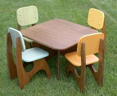 three children's wooden chairs sitting at a table in the middle of some grass