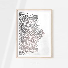 a framed art print with an intricate design in black and white, on a wall