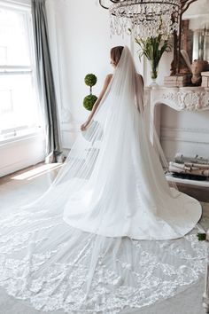 a woman in a wedding dress is standing near a chandelier