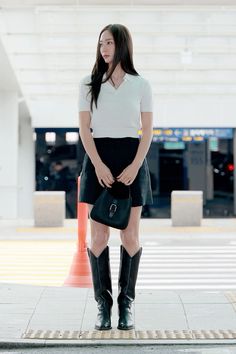 a woman in black and white is standing on the sidewalk