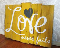 a wooden sign with the word love never fail painted on it in white and black