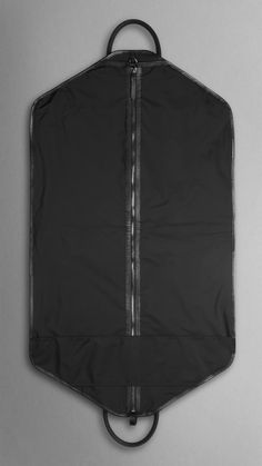 the back of a black garment bag on a gray surface with zippers and handles