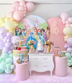 a table topped with lots of balloons and cake next to a wall filled with princesses