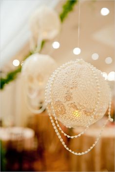 a close up of a white flower with beads on it's head and necklaces hanging from the ceiling