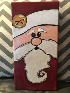 a painting of a santa clause on a red and white pillow with chevron pillows in the background