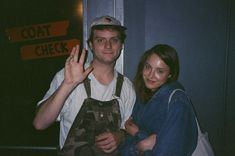 a man and woman standing next to each other in front of a sign that says coat check