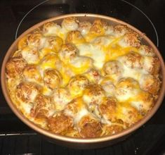 a pizza sitting on top of an oven with cheese and meatballs in the middle