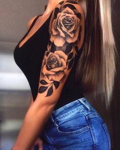 a woman with long hair wearing a black top and roses tattoo on her arm,