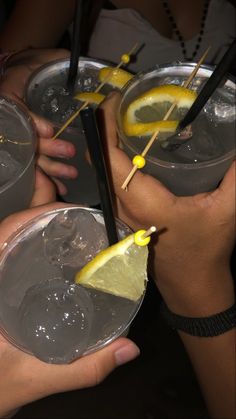 several people holding up glasses with lemon wedges in them