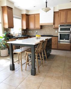 a large kitchen with wooden cabinets and an island table in the middle, surrounded by stools