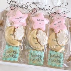 three decorated cookies in plastic wrappers on top of a white tablecloth with twinkies and pink stars