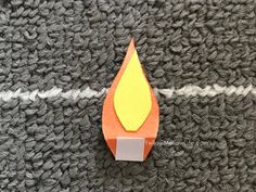 an orange piece of paper sitting on top of a knitted surface next to a white line