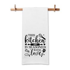 this kitchen is seasoned with love dish towel in black and white on a wooden hanger