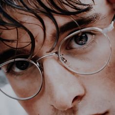 a close up of a man wearing glasses and looking at the camera with an intense look on his face