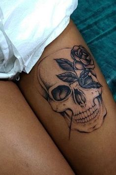 a woman's thigh with a skull and rose tattoo on it