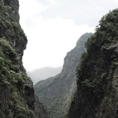 two people riding on the back of a boat down a narrow river surrounded by mountains