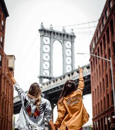 two girls are walking down the street with their arms in the air