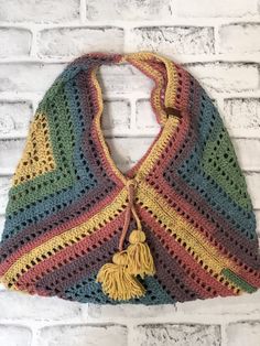 a multicolored crocheted bag hanging on a brick wall