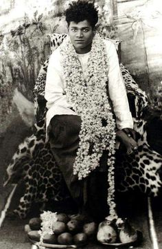 a black and white photo of a man sitting on a chair with fruit in front of him