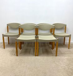 four chairs sitting next to each other on the floor in front of a white wall