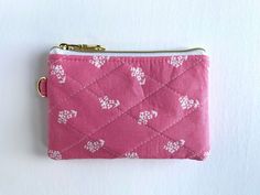 a small pink purse with white hearts on the front and bottom, sitting on a white surface