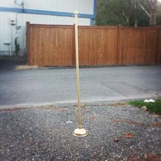 a pole that is standing in the middle of some gravel and grass next to a fence