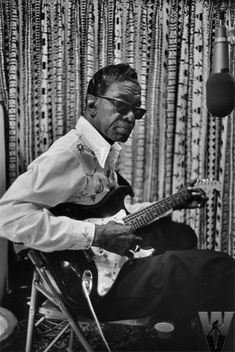 a man sitting in a chair playing a guitar