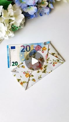 an origami clock sitting on top of a white table next to blue and white flowers