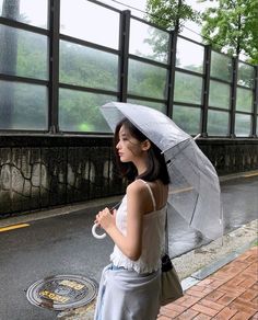 a woman holding an umbrella while standing next to a manhole