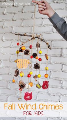 a wind chime made out of pine cones, nuts and acorns with text overlay that reads fall wind chimes for kids