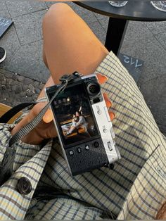 a person sitting down taking a photo with a cell phone in their lap and holding it up to the camera