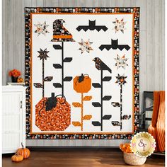 an orange and black halloween quilt hanging on a wall