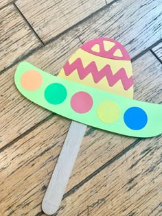 a paper plate with an easter egg on it sitting on a wooden floor next to a stick