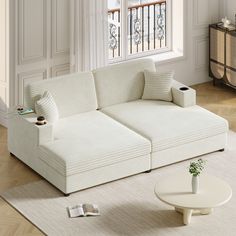 a white couch sitting on top of a wooden floor next to a table and window