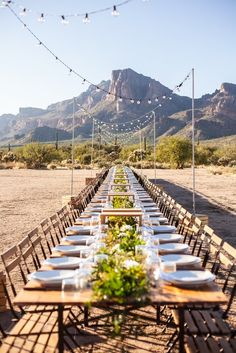 a long table set up with plates and place settings in the middle of an empty desert