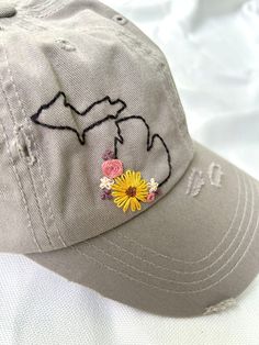 a gray hat with embroidered flowers on it